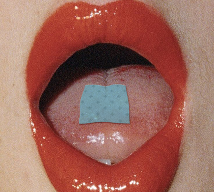 Close-up of a tongue with a blue square patch inside an open mouth.