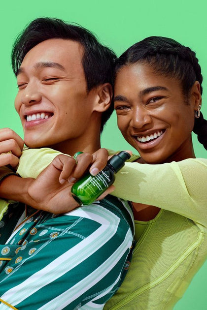 Two people embracing with a green bottle against a bright green background