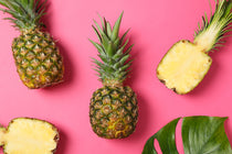 Pineapples and pineapple leaves on a pink background