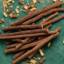 Dried licorice roots on a textured green surface