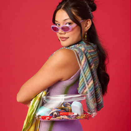 Woman holding a clear bag filled with Wizard Wellness products against a red background