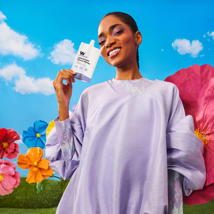 Woman holding the advanced sinus rinse with colorful flowers and sky in the background