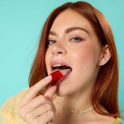 Woman holding Wizard Wellness Multi-Benefit Oral Strips against her tongue.